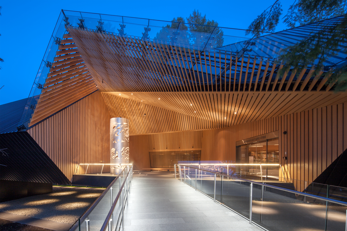 Exterior evening view of multi-angled trapezoidal wood and glass slat entrance to low rise Audain Art Museum, built with laminated strand lumber (LSL) and parallel strand lumber (PSL)