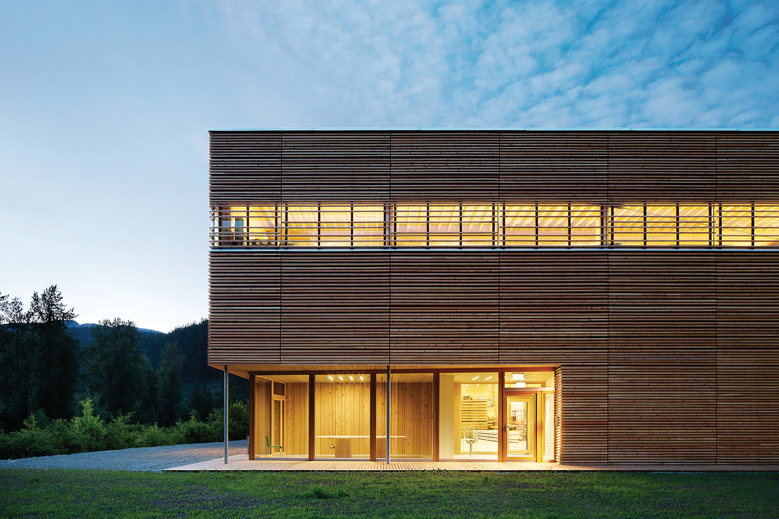 Exterior evening view of BC Passive House Factory, a low rise passive house structure built with light frame and mass timber components such as Cross-laminated timber (CLT), I-beams, I-joists, and hybrid / wood