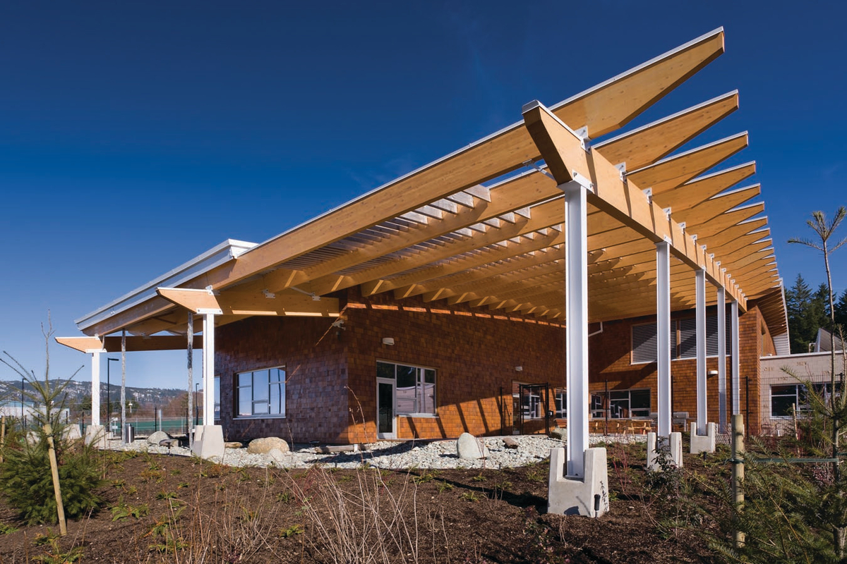 Sunny daytime exterior view of 2,100 square metre BC Hydro Operations Centre in Port Alberni showing wood exterior, including a roof of braced, steel frame supporting glue-laminated timber (glulam) beams on the main column lines
