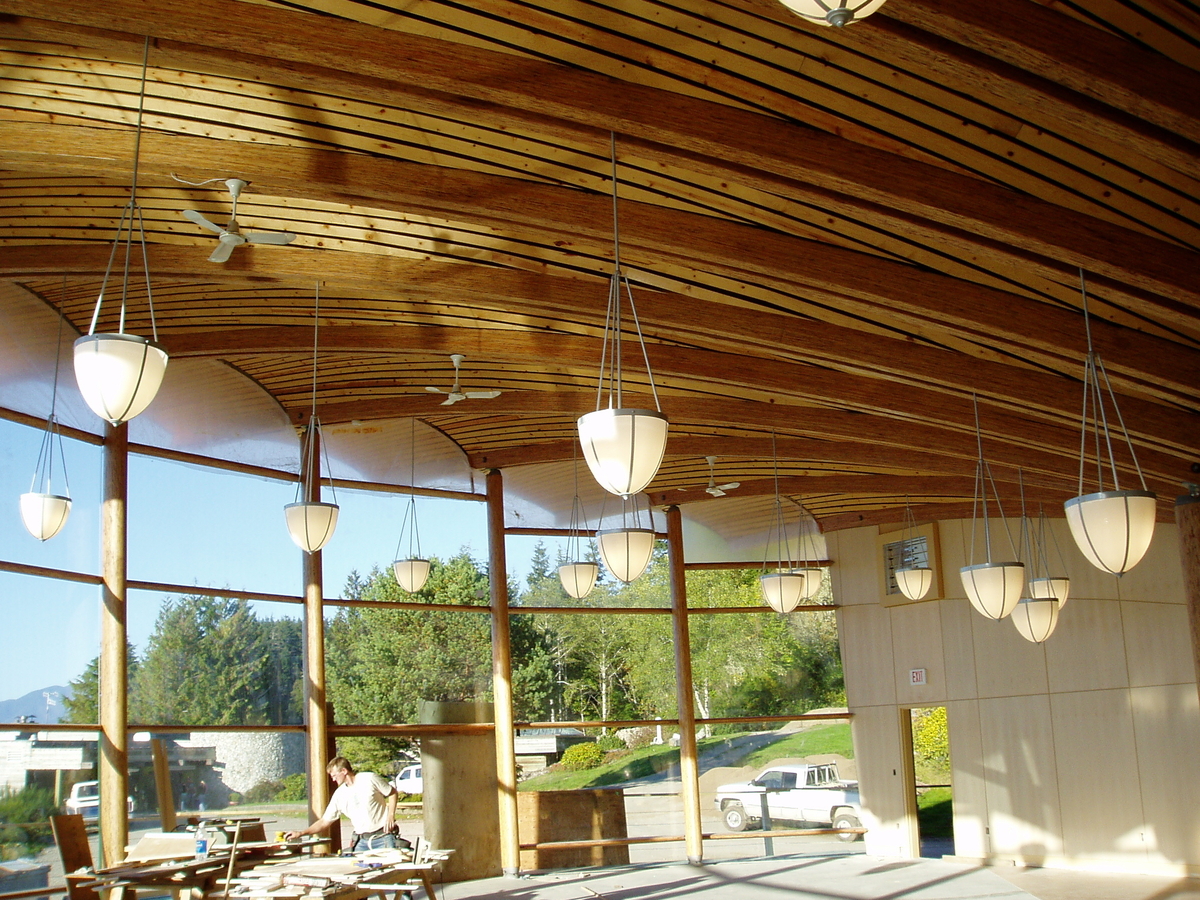 Interior daytime view of Bamfield Marine Centre central room looking out through expansive curved glass with scallop-shell-shaped wood roof above