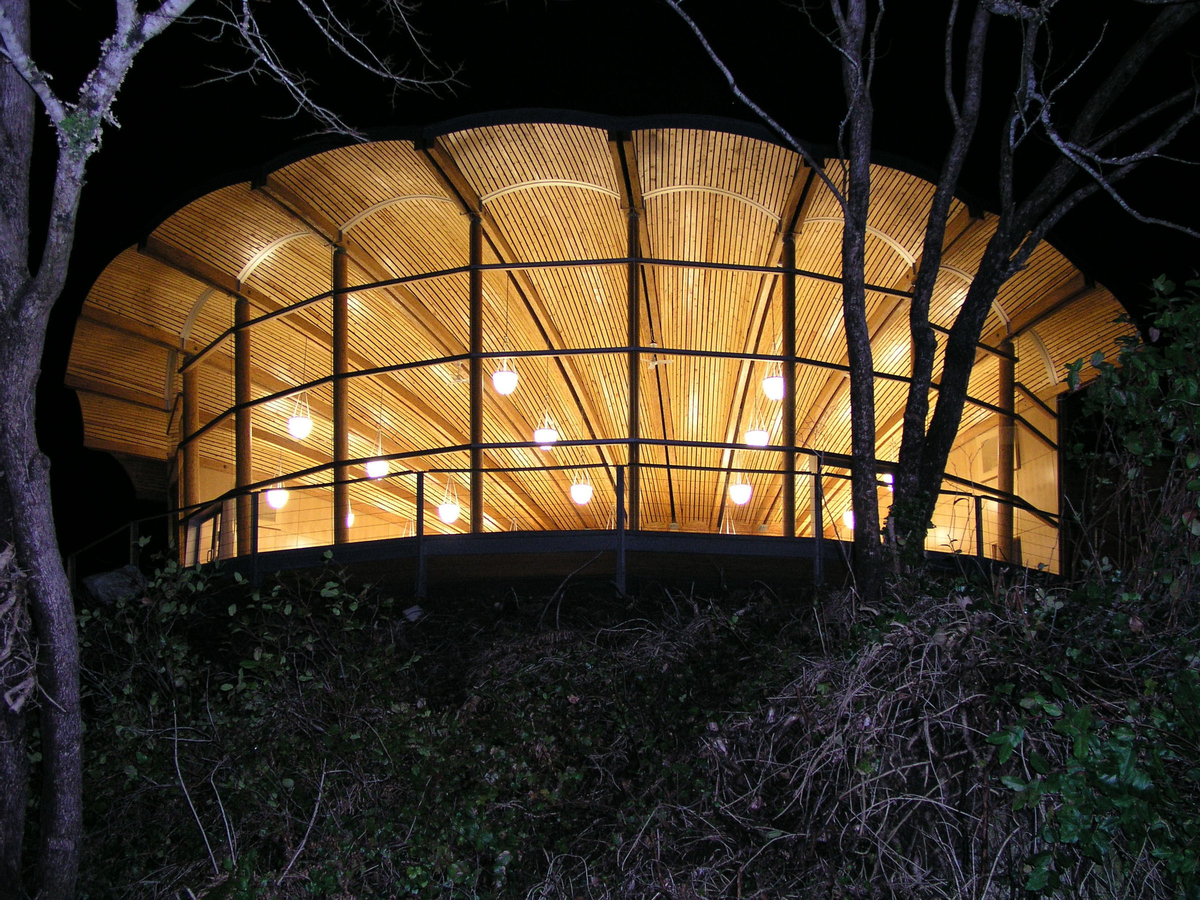 Nighttime exterior view of Bamfield Marine Centre, looking in at scallop-shell-shaped wood roof with parallel strand lumber (PSL) bottom chords