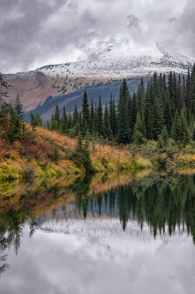 Wilderness lake with trees and snow topped mountain in background