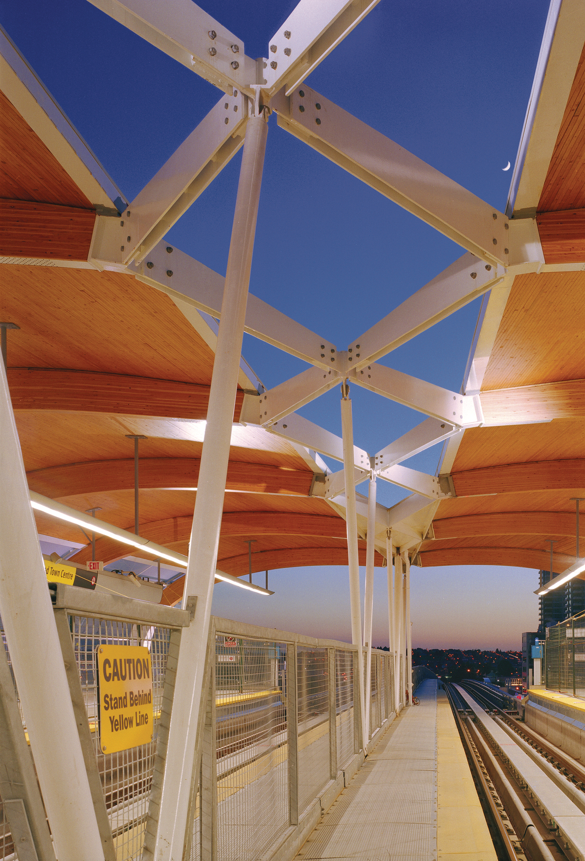 Large arching nail laminated timber (NLT) beams supporting a wooden ceiling are prominent features in this interior view of the City of Burnaby's Brentwood transit station