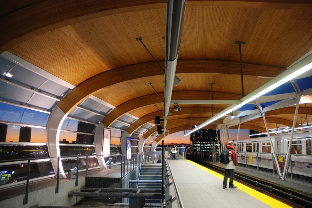 Large arching nail laminated timber (NLT) beams supporting a wooden ceiling are prominent features in this interior view of the City of Burnaby's Brentwood Town Centre Transit station