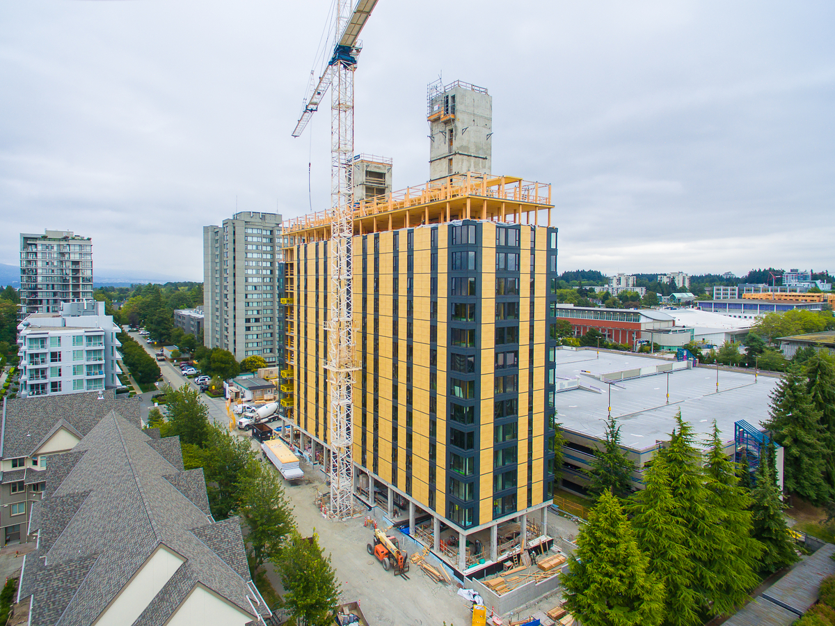 Exterior overcast daytime drone view of nearly completed Brock Commons Tallwood House with prefabricated exterior wall panels and wood-fibre-and-resin cladding in place on many floors