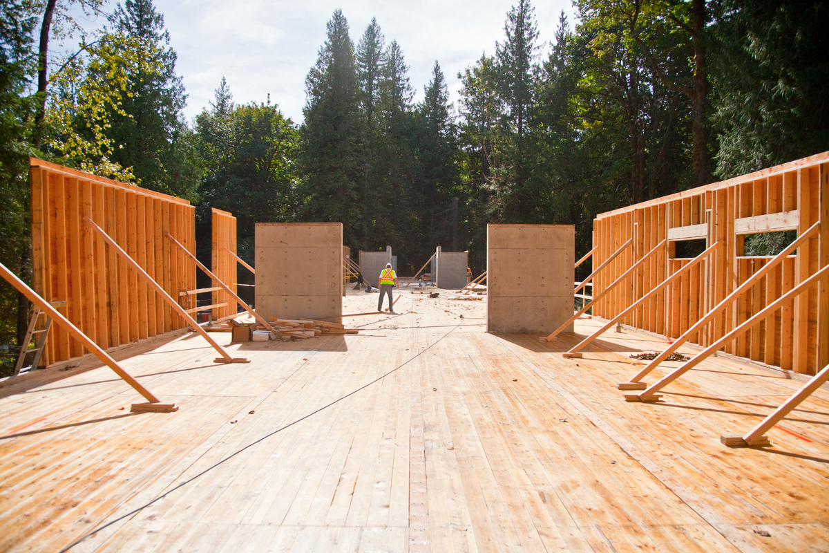 Early construction exterior daytime view of Cheakamus Centre Blueshore Environmental Learning Centre showing wooden subfloor and prefabricated exterior wall panels