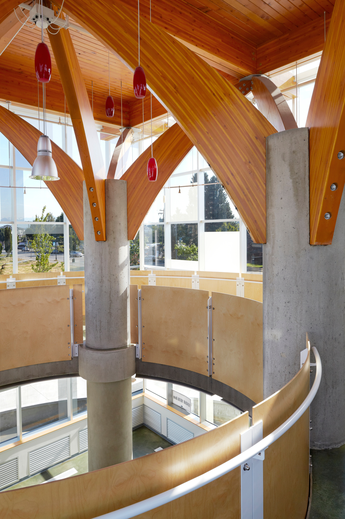 Interior sunny afternoon view of low rise Chuck Bailey Recreation Centre featuring massive structural Glue-laminated timber (Glulam) roof supports atop concrete columns