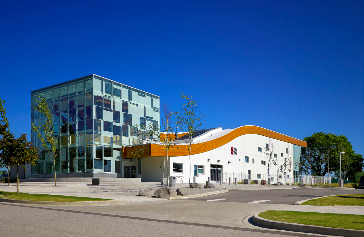 Exterior mid day view of low rise Chuck Bailey Recreation Centre featuring sloped roof with massive structural Glue-laminated timber (Glulam) accent