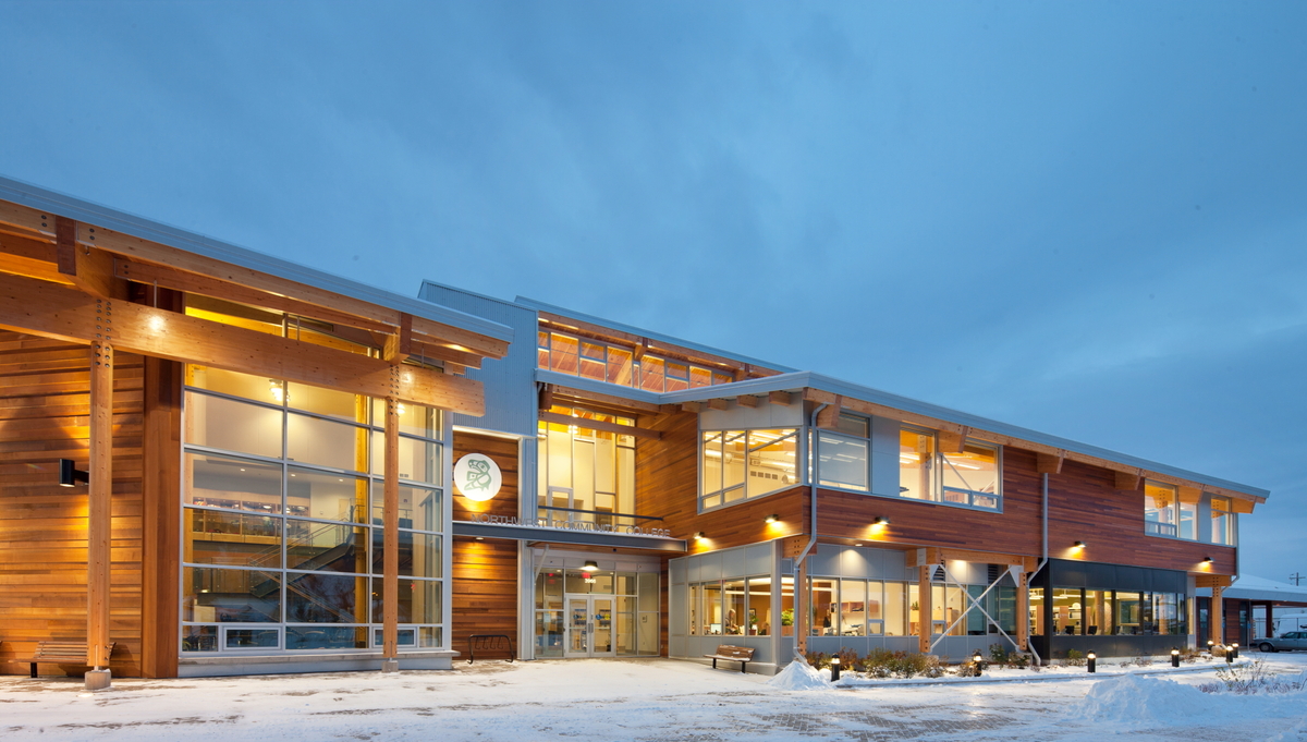 Exterior snowy early evening view of Coast Mountain College showing significant use of lumber siding, glue-laminated timber (glulam) beams and solid-sawn heavy timbers