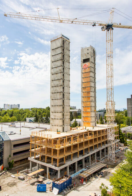 Early daytime construction aerial view of Brock Commons Tallwood House showing completed central elevator shafts protruding above cross-laminated timber (CLT) floor panels being set in place