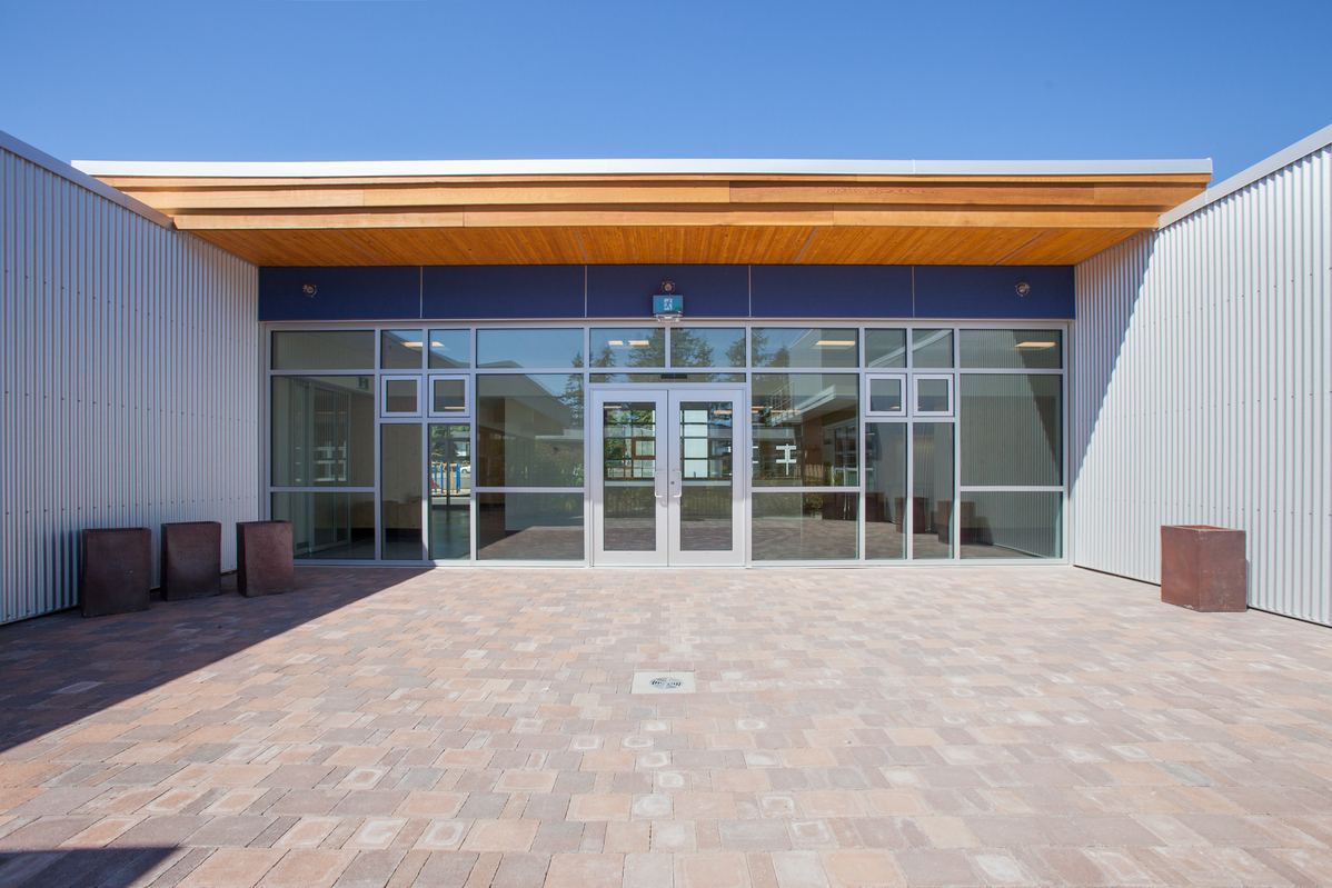 Exterior daytime view of Cordova Bay Elementary School covered entrance showing hybrid construction of steel, glass, and prefabricated panelized wood building systems composed of nail-laminated timber (NLT) and cross-laminated timber (CLT)