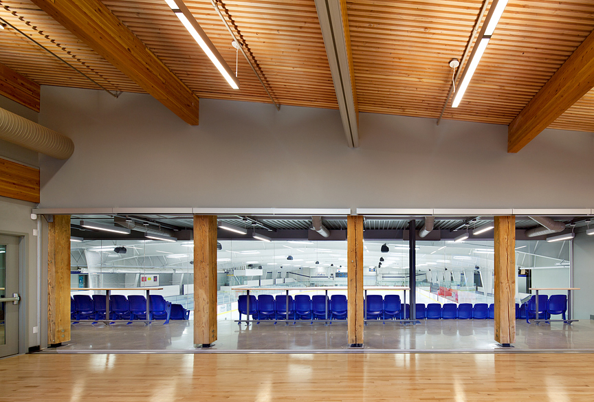 Interior view of Cowichan Lake Sports Arena, showing main entrance constructed with heavy timber, glue-laminated timber (glulam) beams, and solid-wood decking