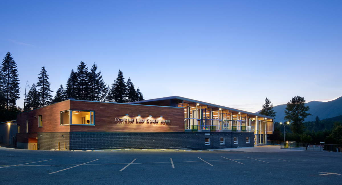 Exterior evening view of Cowichan Lake Sports Arena, showing heavy timber, glue-laminated timber (glulam) beams, solid-wood decking and western red cedar cladding