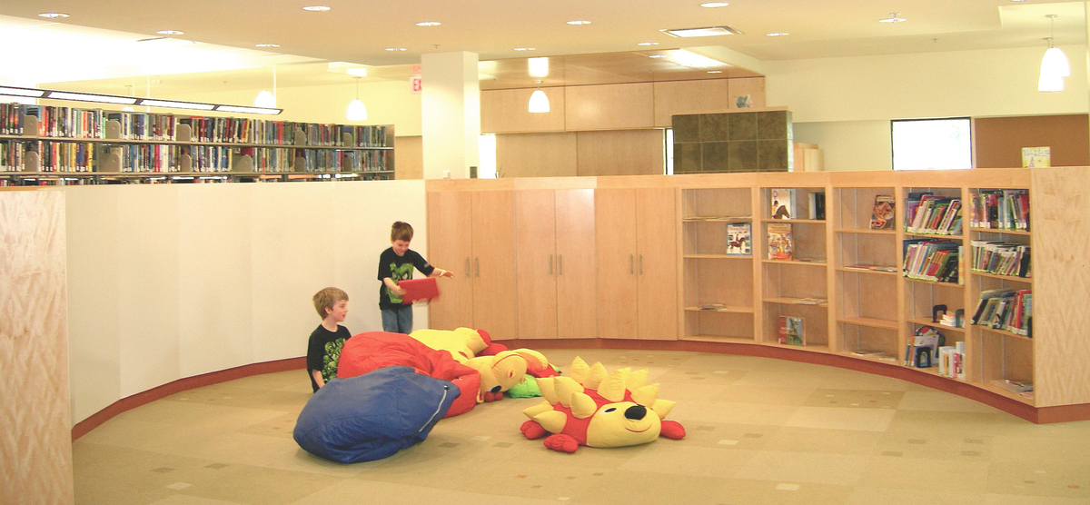 Interior view of Cranbrook Public Library showing wooden millwork and paneling accents in warm and welcoming raised children's reading and play area