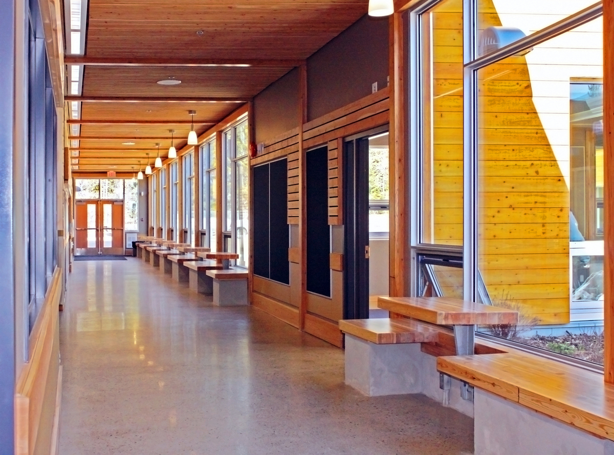 Interior view of low rise Crawford Bay Elementary-Secondary School main hallway showing hybrid construction utilizing paneling, post + beam, and a roof of stacked wood planks