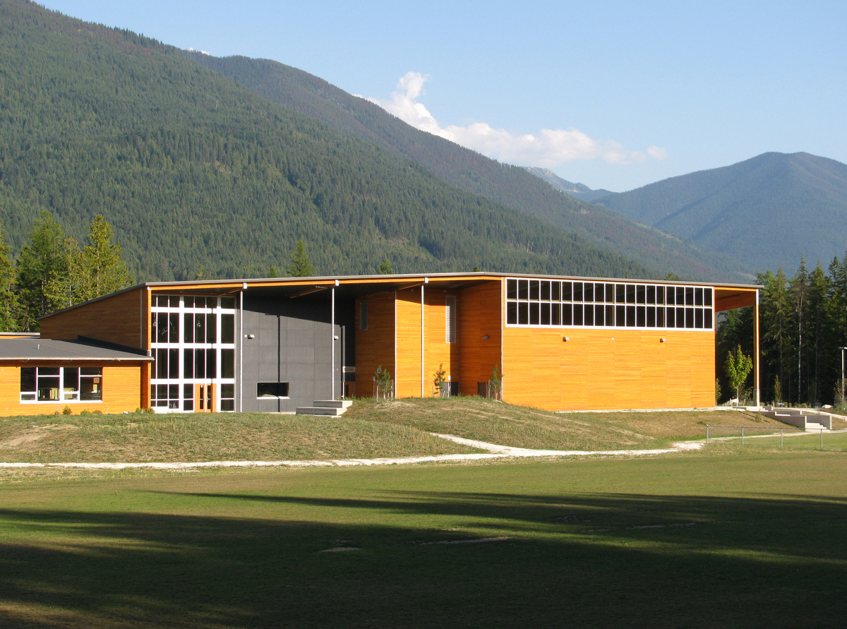 Exterior overall view of low rise Crawford Bay Elementary-Secondary School showing metal and wood hybrid construction with wood paneling, post + beam, and a roof overhang prefabricated on site from stacked wood planks and glulam beams