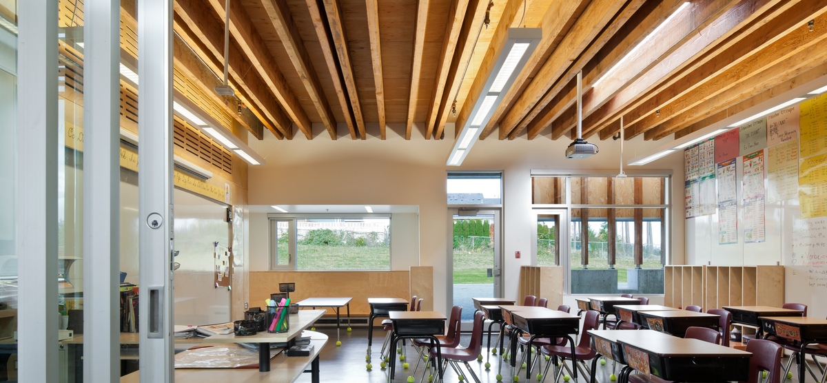 Interior daytime view of low rise École Mer-et-Montagne elementary school classroom, showing exposed Douglas-fir timbers and wood accents