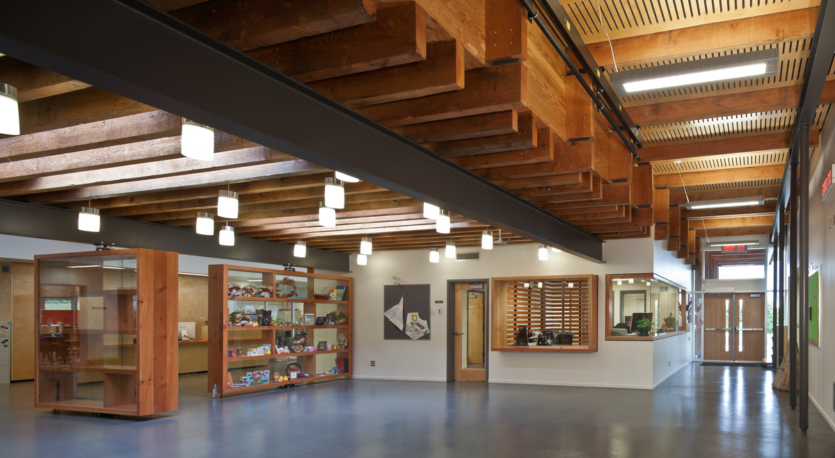 Interior daytime view of low rise École Mer-et-Montagne elementary school main entrance hall and office, showing exposed Douglas-fir timbers and extensive wood accents