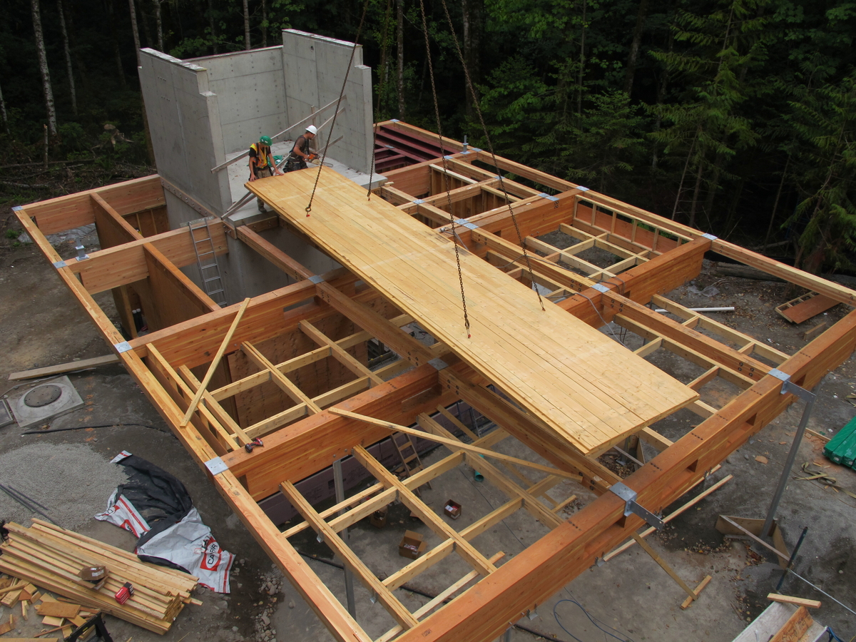 Exterior early construction daytime aerial view of Elkford Community Conference Centre showing Glue-laminated timber (glulam) and laminated veneer lumber (LVL) beam grid with cross-laminated timber (CLT) floor panel being lowered into place