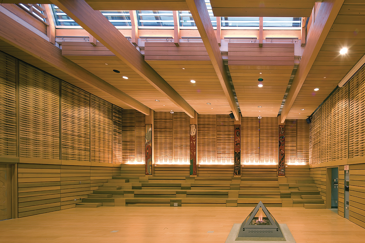 Interior daytime view of The First Peoples House at the University of Victoria showing extensive use of paneling and mass timber, including Douglas-fir glue-laminated timber (glulam) beams and columns which support a sloping roof