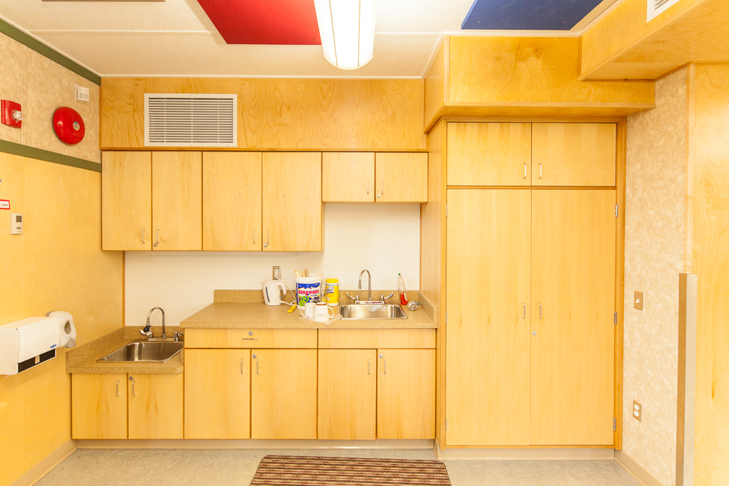Interior view of Full Day Kindergarten Classroom kitchenette area showing wood cabinetry and ducting