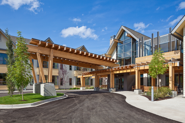 Exterior sunny view of glue-laminated timber (Glulam) and post + beam covered drive through entrance at Gateway Lodge Long-Term Care