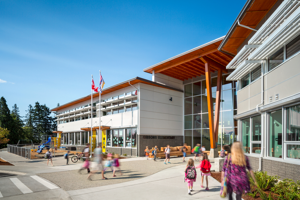 Glue laminated timber beams and columns support the cantilever roof overhang in this exterior view of Gibsons Elementary School as children enter on a sunny day