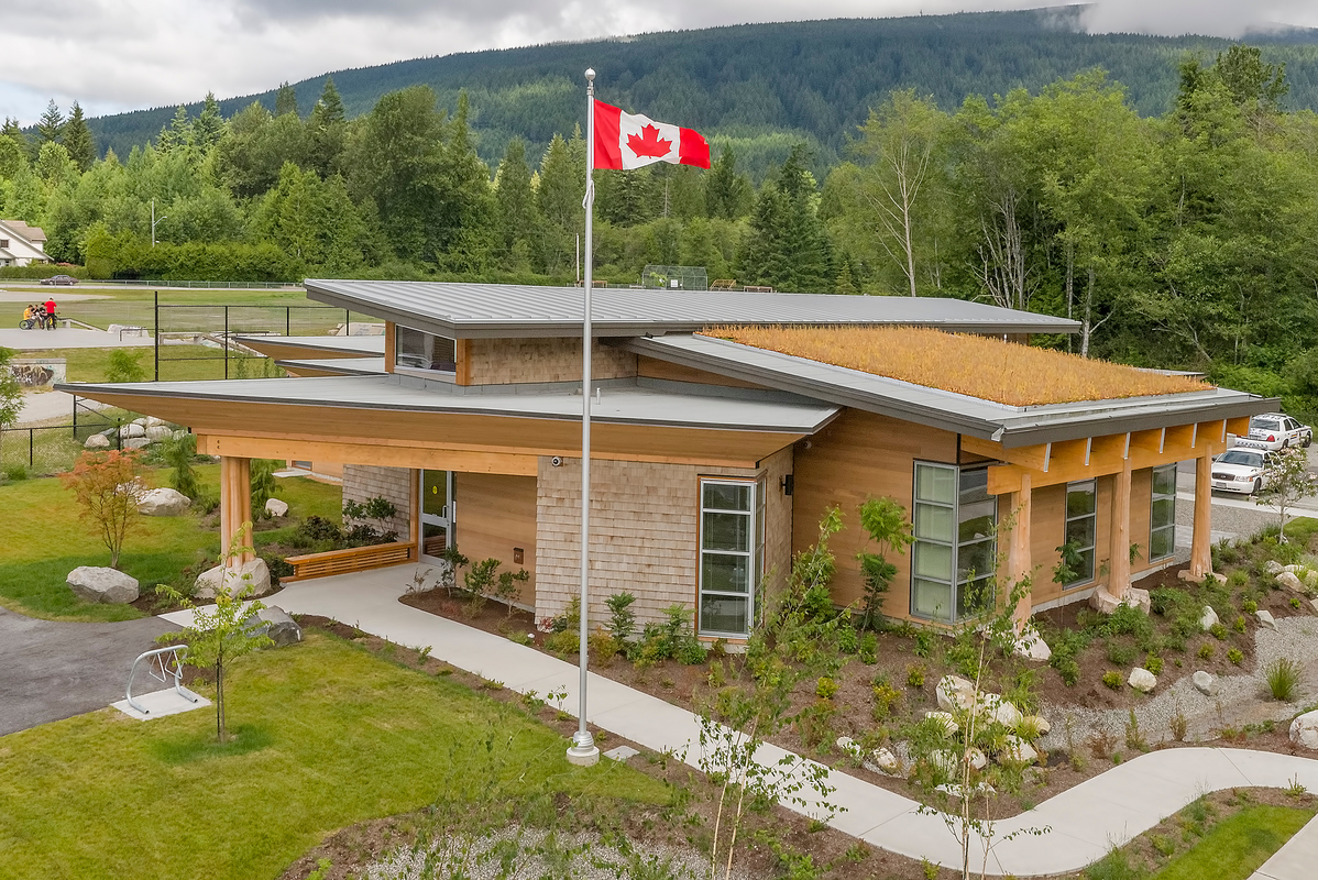 Exterior overcast daytime aerial view of low rise Gibsons RCMP Facility showing glue-laminated timber (glulam) beams extending from eves and supported by post and beam