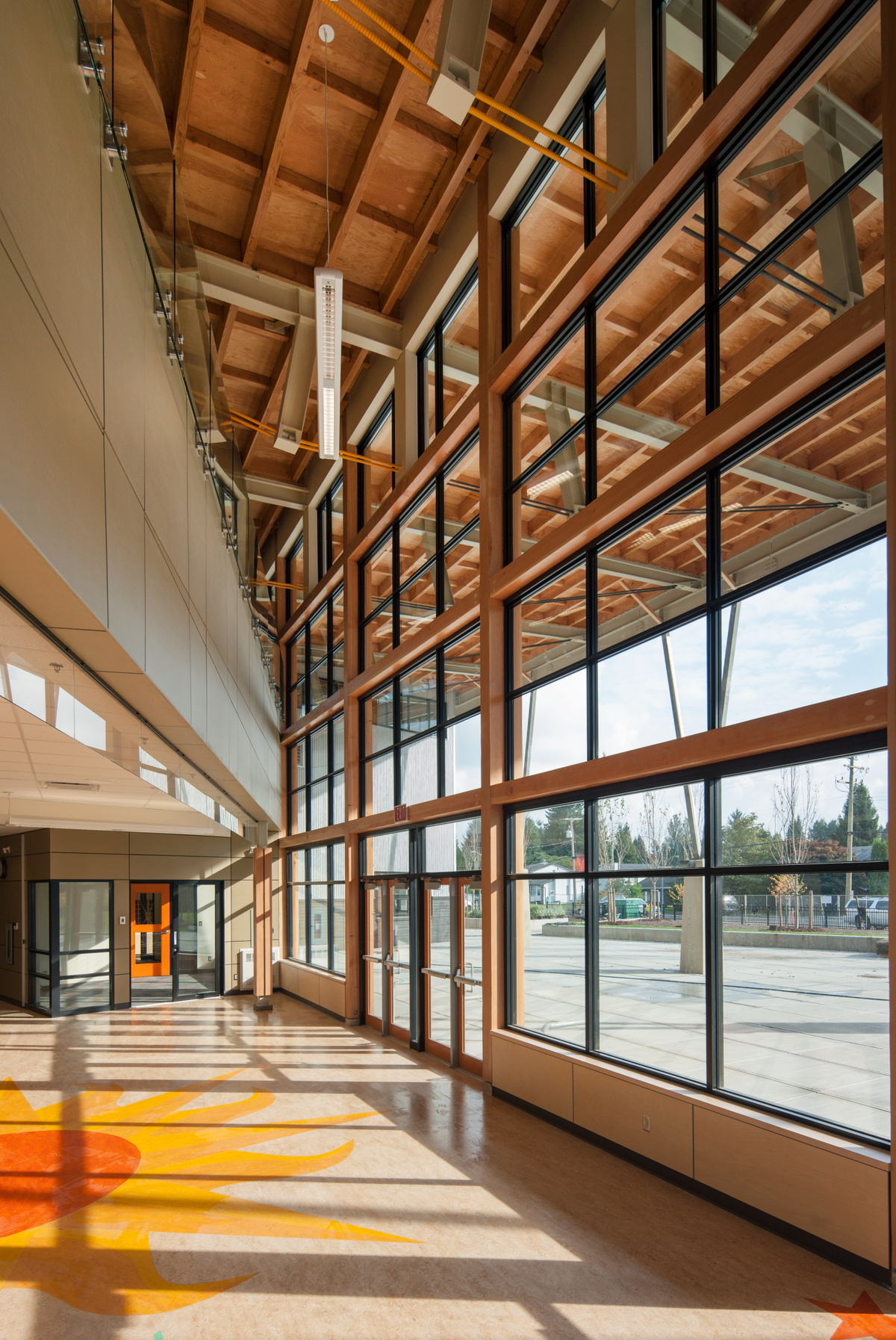 Interior daytime view of low rise hybrid James Park Elementary School main entrance, showing glass, steel, and exposed wood ceiling construction, which provides warmth and beauty to this state-of-the-art, LEED certified, energy-smart building