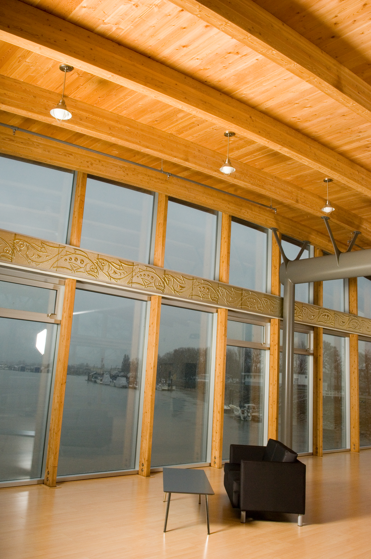 Interior close up daytime view of John M.S. Lecky UBC Boathouse ceiling and expansive glass exterior wall, showing a combination of steel, glue-laminated timber (glulam), and lumber light frame roofing construction
