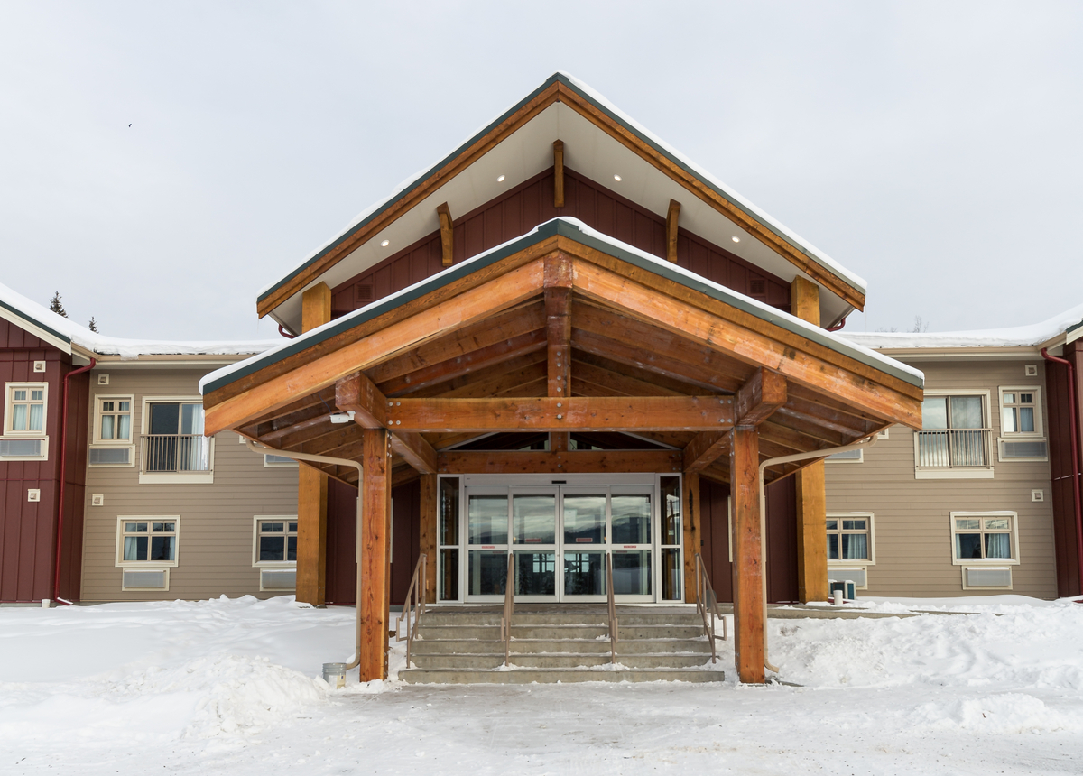 Exterior snowy daytime view of Key-oh Lodge, showing tiered main entrance and covered stairway, constructed of lumber, solid-sawn heavy timber, and trusses