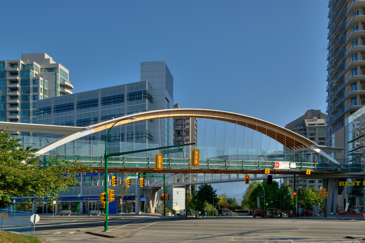 Exterior daytime view of Kingsway Pedestrian Bridge showing double-curved glue-laminated timber (glulam) arch with walkway suspended by steel cables below