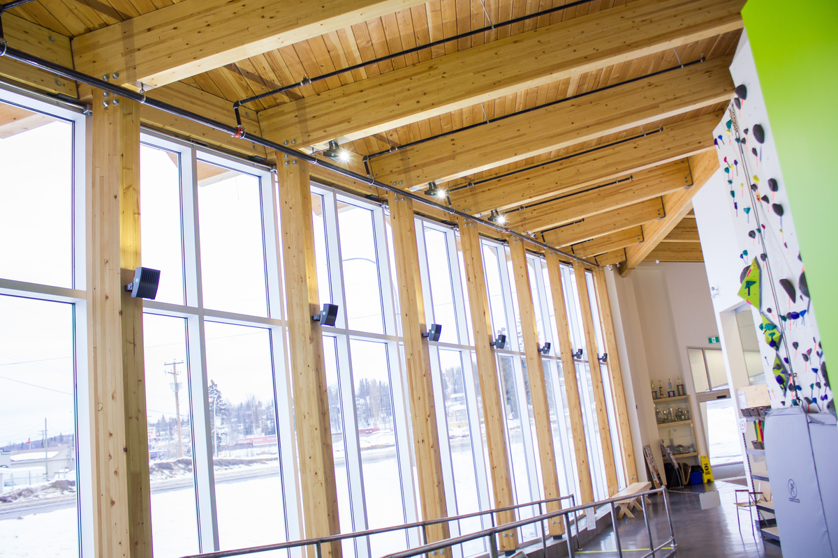 Sunny interior winter image of Burns Lake Lakeside Multiplex showing exposed roof structure of solid plank decking and glue-laminated timber (glulam) beams and supporting columns