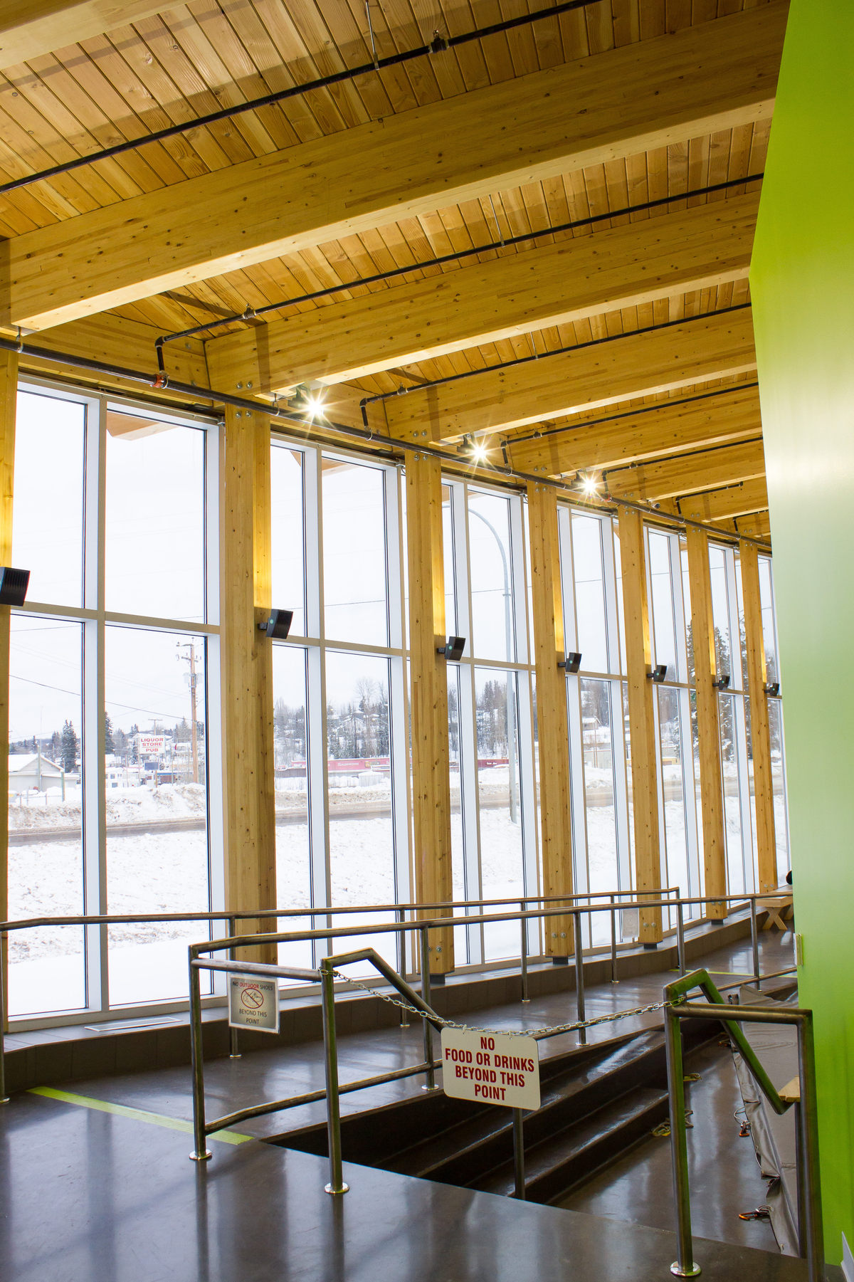 Sunny interior winter image of Burns Lake Lakeside Multiplex showing exposed roof structure of solid plank decking and glue-laminated timber (glulam) beams and supporting columns