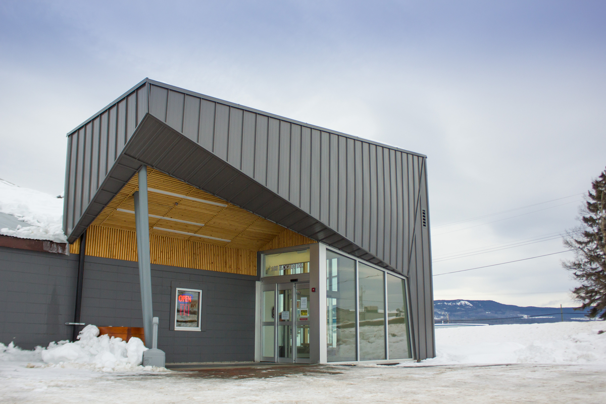 Sunny exterior winter image of low rise Burns Lake Lakeside Multiplex main entrance, showing exposed roof structure of solid plank decking and exterior metal cladding