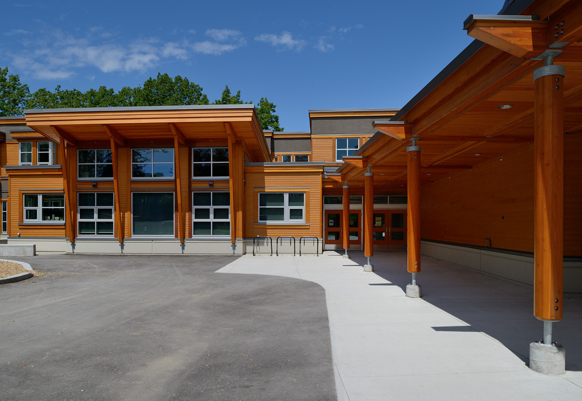 Exterior daytime view of two storey Lord Kitchener Elementary School showing extensive wood use, including glue-laminated timber (glulam) beams, millwork, paneling, and siding