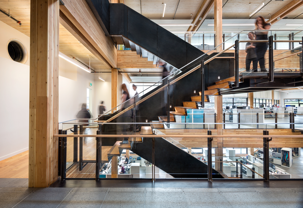 Interior daytime view of occupied Mountain Equipment Co-op Head Office showing half turn stairwell as example of nail-laminated timber (NLT) application