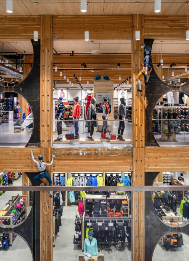 Interior completed view of MEC Van Flagship retail location showing glue-laminated timber (Glulam) beams, columns, and various timber supports; also features people, clothing, and climbing demonstration