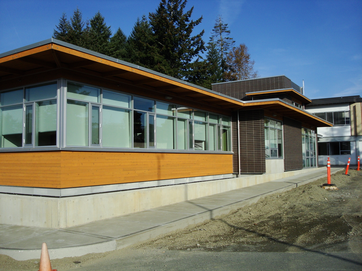 Exterior sunny daytime view of nearly completed North Cowichan Municipal Hall which features hybrid mass timber construction comprised of glue-laminated timber (glulam) beams, supported by steel columns