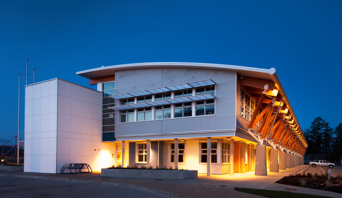 Exterior evening view of North Saanich Middle School showing hybrid metal, wood and concrete construction and including solid mass timber paneling, post + beam, and Glue-laminated timber (Glulam)