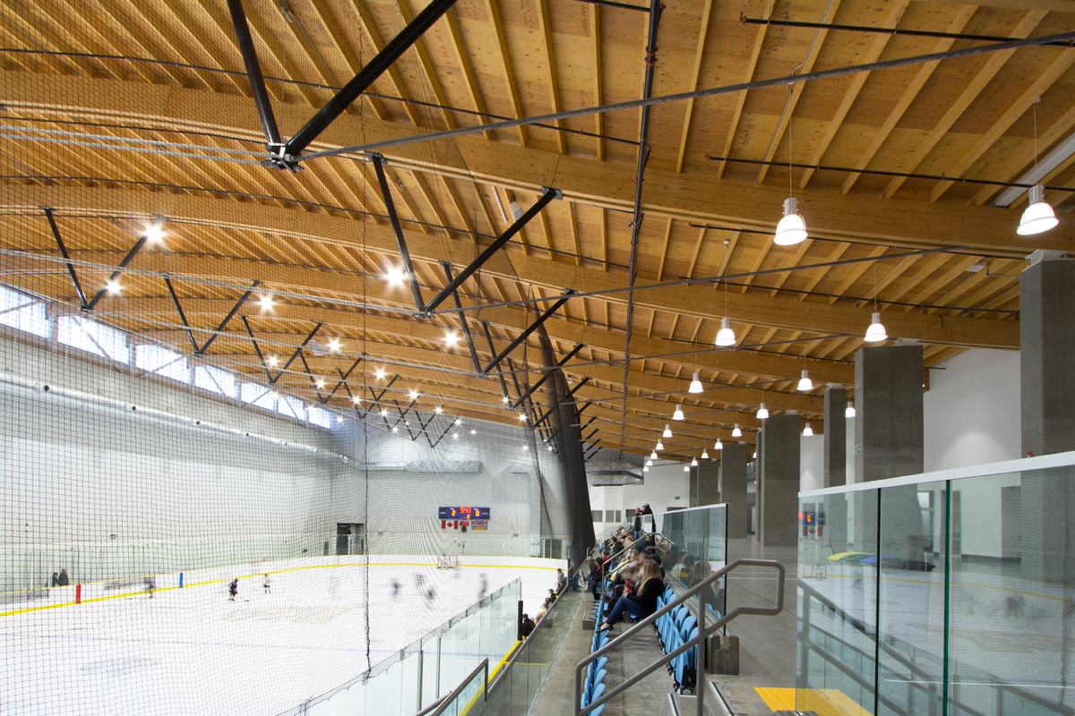 Interior sunny daytime view of occupied low rise North Surrey Sport and Ice Complex showing curved 'wave' roof profile using glue-laminated timber (Glulam)