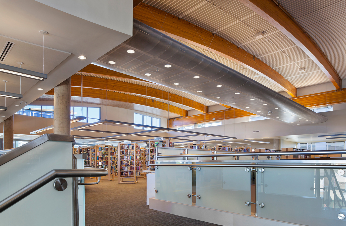 Interior daytime view of Okanagan Regional Library showing long-span glue-laminated (glulam) roof beams, which minimize the need for internal column supports, and slatted wood ceilings to reduce ambient noise