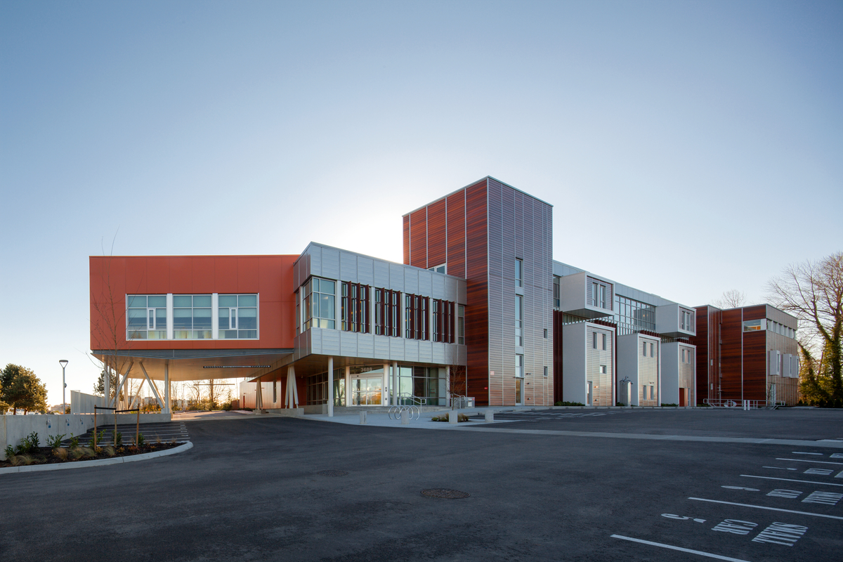 Exterior sunny view of three-storey low rise mass timber constructed Pacific Autism Family Centre showing warm exterior of Douglas-Fir and Western Red Cedar