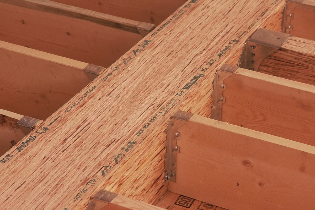 Close up interior view of parallel strand lumber (PSL) beam with attached metal hangers and floor joists