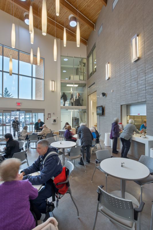 Parkinson Activity Centre with vaulted ceilings, white walls, dangling light fixtures and people socializing