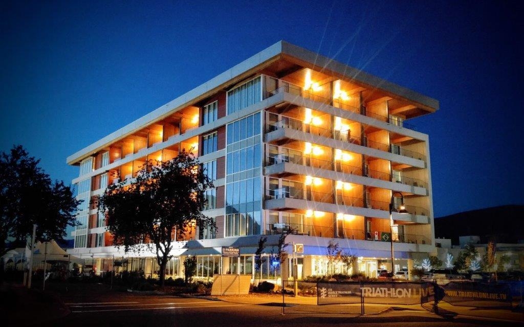 Mass timber constriction, post & beam, CLT (cross-laminated timber) & prefabrication are prominently featured in this nighttime exterior view of the Penticton Lakeside Resort West Wing mid rise
