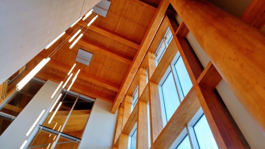Upward interior multi floor atrium ceiling view within The West Wing, Penticton Lakeside Resort and Conference Centre showing artistic drop lights and highlighting extensive use of exposed glue-laminated timber (glulam) and cross-laminated timber (CLT)