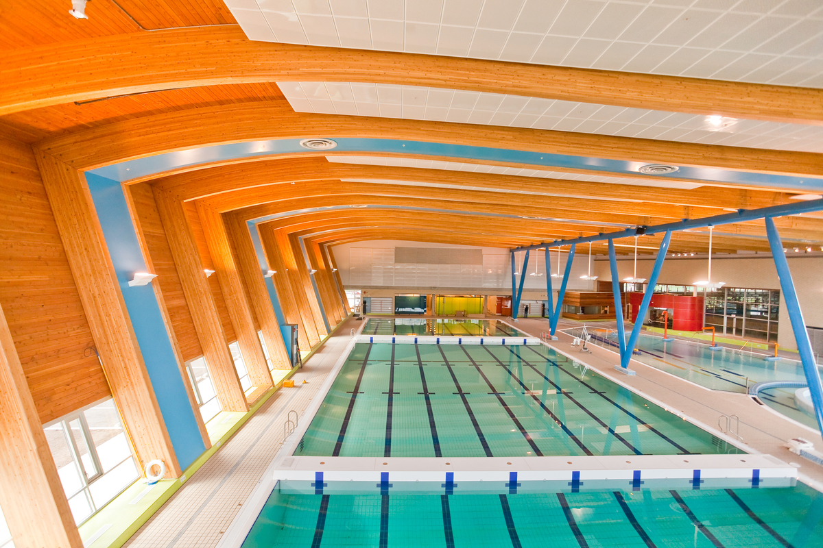 Interior daytime view of expansive low rise Percy Norman Pool Hillcrest showing glue-laminated timber (Glulam) columns and ceiling beams in addition to prefabricated paneling accents