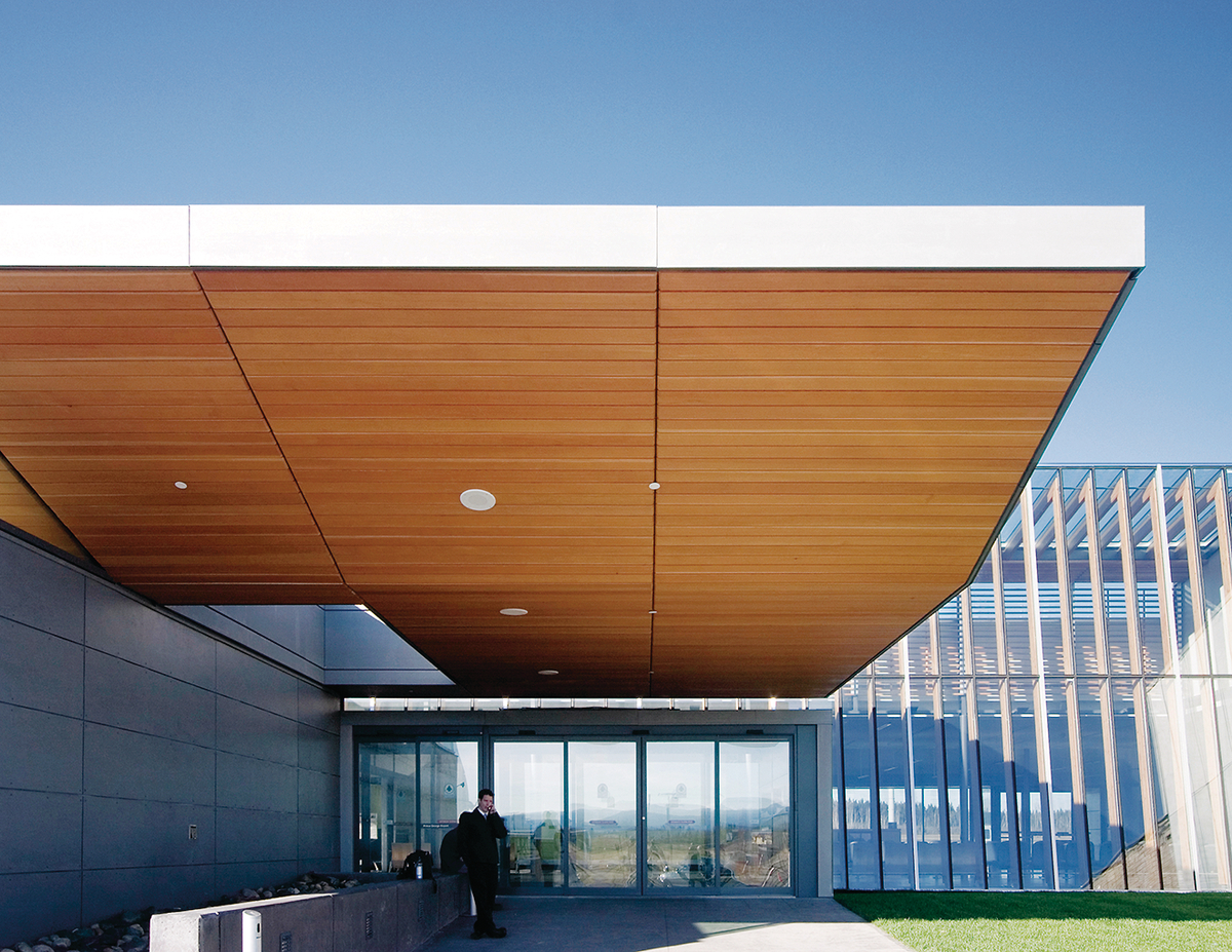 Glue-laminated timber (Glulam), and decorative plywood ceiling paneling bring structure and warmth to this daytime exterior view of the Prince George Airport Expansion entrance roof