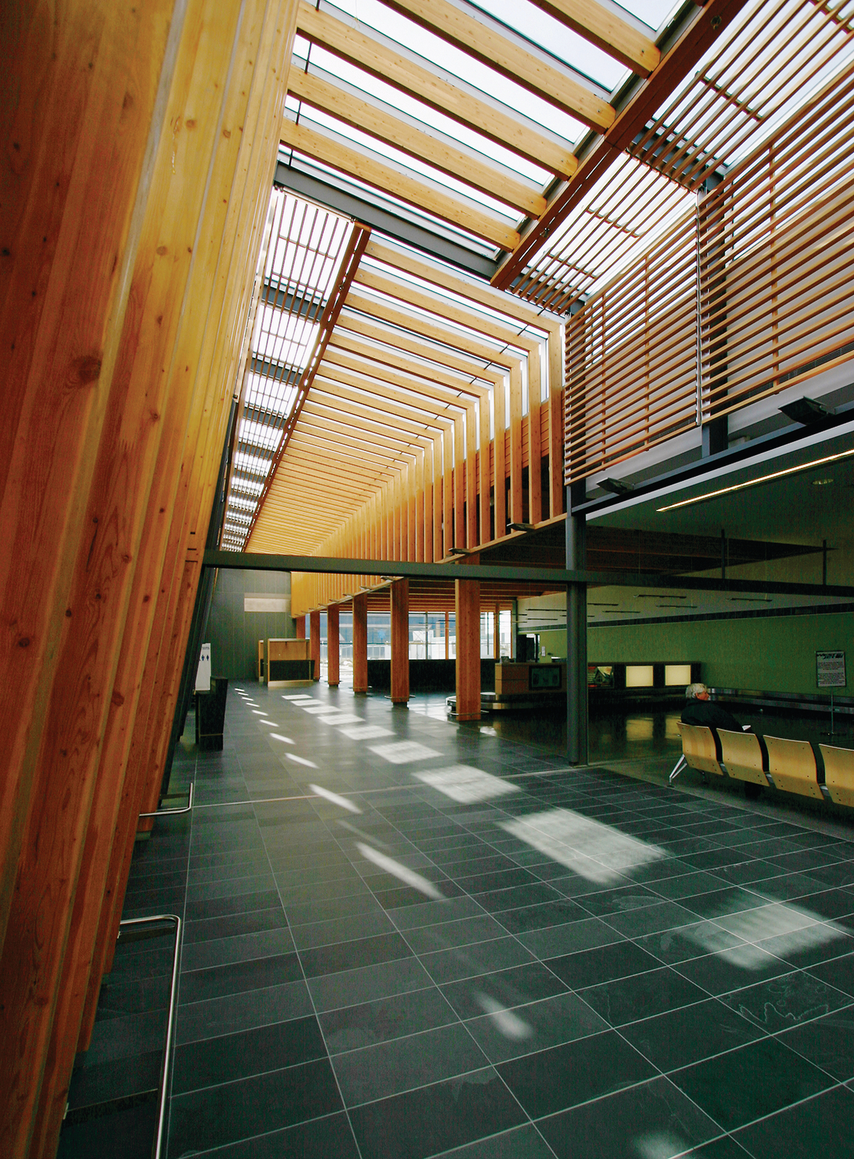 Interior daytime view of low rise Prince George Airport Expansion showing glue-laminated timber (glulam) beams and columns mixed with artistic dimensional lumber slats